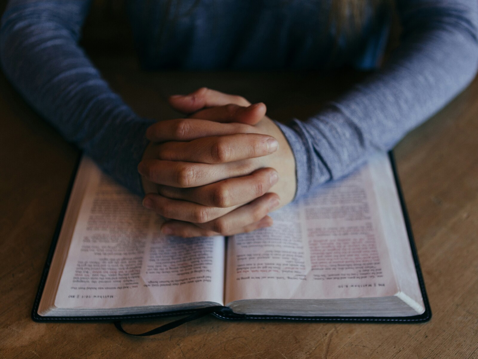 A person praying over an open Bible